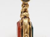 a gold charm with a red, green, and yellow bead