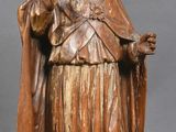 wooden statue of a man in a robe and hat holding a cane