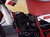 a red and white motorcycle parked next to a white wall