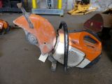 an orange and black machine in a garage with other tools