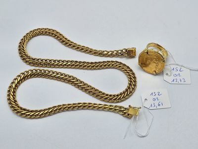 gros plan d'une chaîne en or sur laquelle se trouve une pièce de monnaie