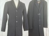 pair of men ' s coats on a mannequin stand in front of a white wall