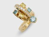 un gros plan d'une bague en or sertie de pierres de différentes couleurs