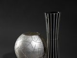 black and white photograph of a vase and a soccer ball on a black background