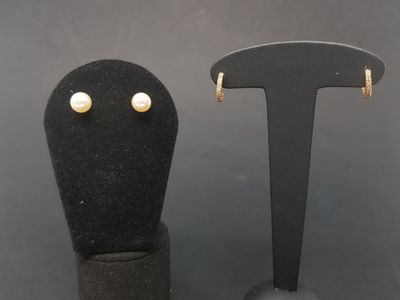 two pairs of earrings are sitting on a black display stand