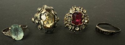 trois bagues et une bague sertie d'une pierre, posées sur une table