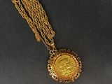 Gros plan sur un collier en or sur lequel se trouve une pièce de monnaie