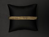 un bracelet en chaîne d'or posé sur un coussin noir