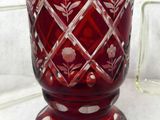 a red glass vase sitting on a table next to a glass block