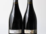 deux bouteilles de vin posées sur une table l'une à côté de l'autre