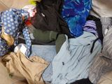 a pile of clothes sitting on the floor next to a suitcase