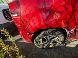 a red car that has been dented and is parked in a lot