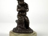 statue of a boy sitting on a rock with his hands on his knees