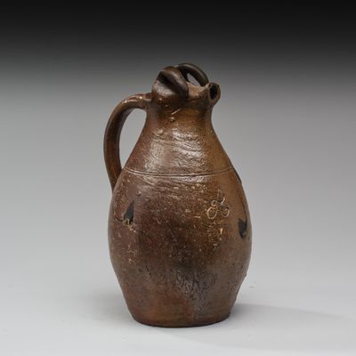 un vieux vase marron muni d'une anse, posé sur un fond blanc
