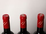 three bottles of red wine are lined up on a table