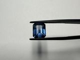 a close up of a pair of pliers holding a blue sapphire