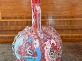 a red vase sitting on a table with a wooden wall in the background