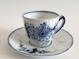 a blue and white cup and saucer on a white table