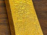a bar of gold sitting on a table next to a piece of paper
