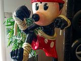 statue of mickey mouse holding a baseball bat in front of a potted plant