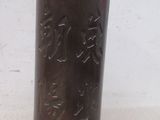 un vase marron portant une inscription, posé sur une surface blanche