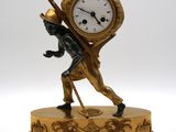 une statue représentant un homme portant une horloge sur le dos