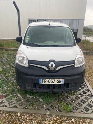 une camionnette blanche garée devant un immeuble, sur un parking