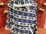 blue and white sweater on a bed with a flower arrangement in the background