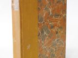 an old book sitting on top of a white table next to a white wall