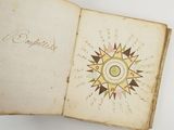 an old book with a compass on it sitting on top of a table