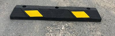 une barrière en plastique jaune et noire posée au sol dans un parking