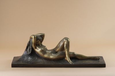 a bronze statue of a woman laying down on her stomach