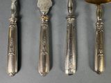 three spoons and a ladle are lined up on a table