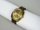 une montre en or posée sur une serviette blanche, sur une table blanche