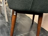grey upholstered chair with wooden legs in a showroom