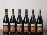 six bottles of wine are lined up on a wooden table