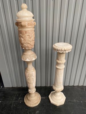 pair of carved stone pedestals on a black floor