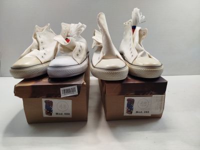 une paire de Converse blanches ornées de nœuds, posées sur des cartons