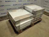 Plusieurs cartons contenant des matelas sont empilés sur une palette devant un mur.