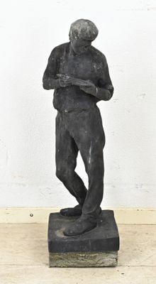 statue d'un homme debout sur un socle, les bras croisés