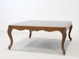 une photo d'une table en bois avec un plateau en verre, posée sur un sol blanc