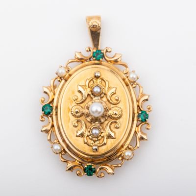a close up of a gold locke with emeralds and pearls