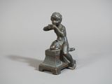 une petite statue représentant un garçon assis sur un tabouret