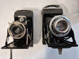 two old cameras sitting side by side on a table