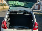une voiture blanche dont le coffre est ouvert, garée sur un parking