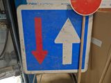 a blue sign with a red arrow and a white sign with a red arrow
