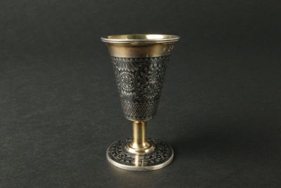 une coupe en argent bordée d'or, posée sur une surface noire