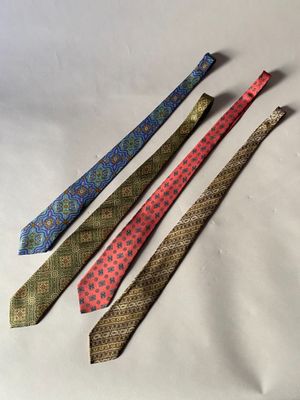 quatre cravates de couleurs différentes sont alignées sur une surface blanche