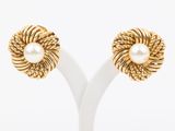 a pair of gold and pearl earrings on a white stand