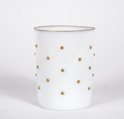 a close up of a white cup with gold dots on it
